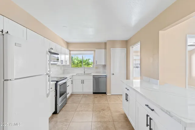 an empty room with chandelier fan and windows