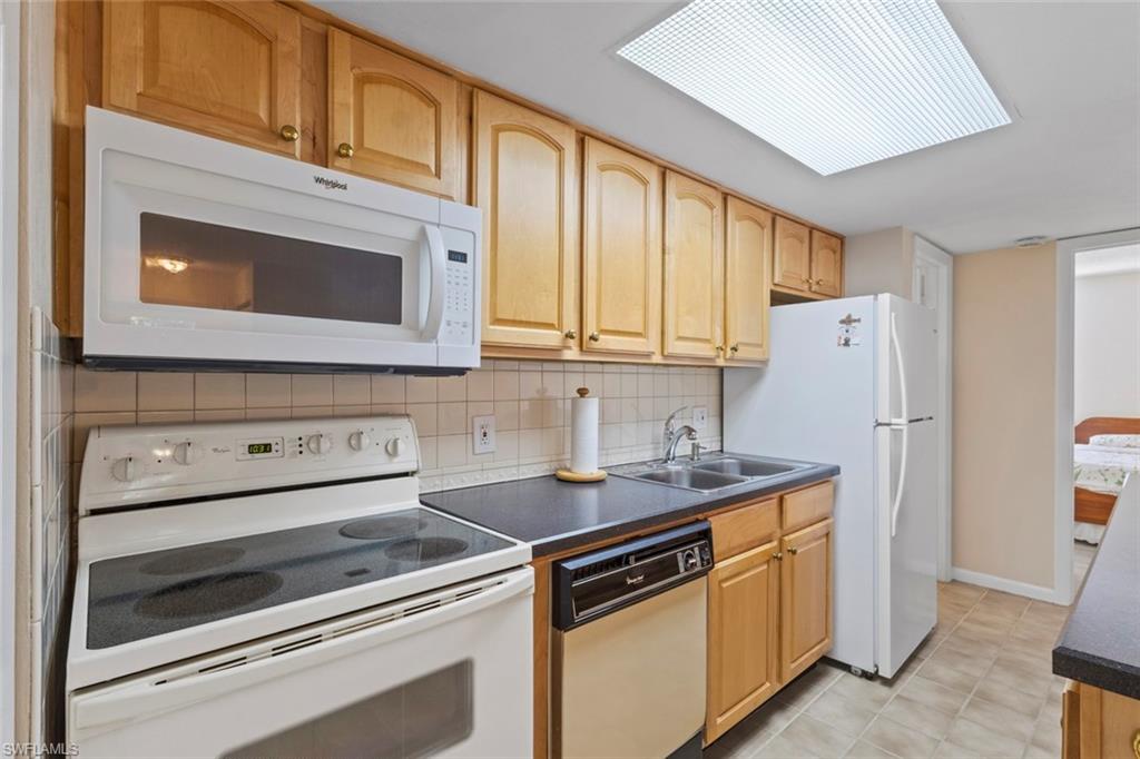 248 Palm Drive, Unit 5 Naples, FL 34112 - Photo 12 of 37 a kitchen with stainless steel appliances granite countertop a stove microwave and refrigerator