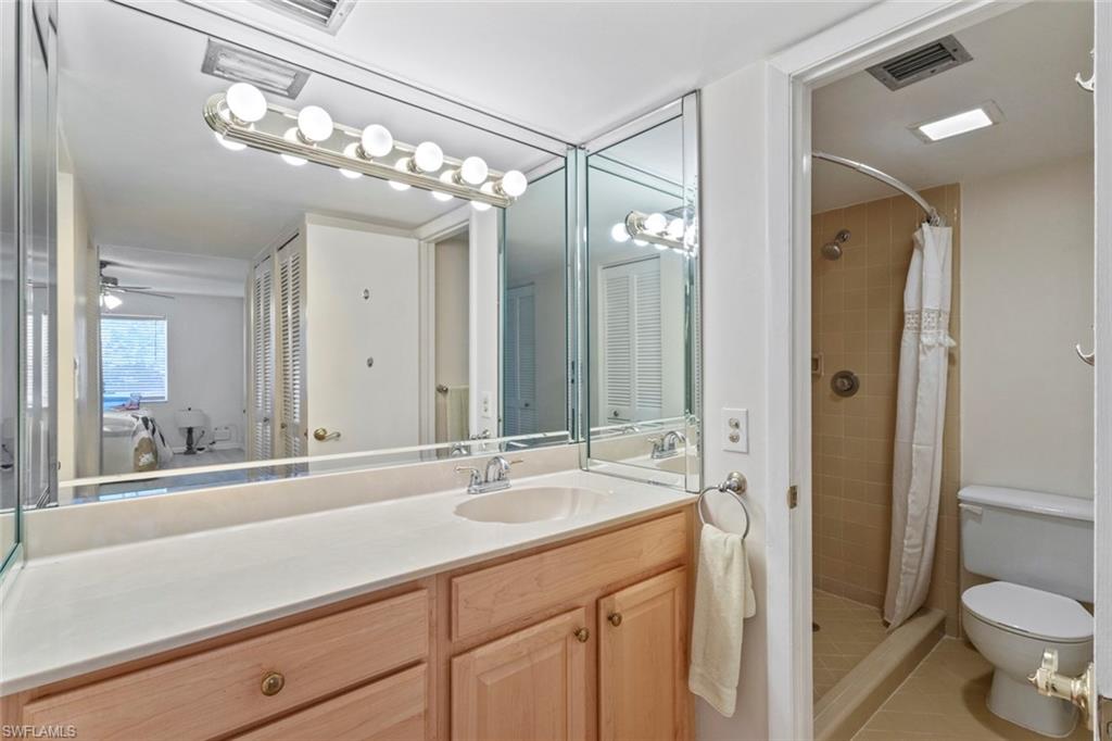 248 Palm Drive, Unit 5 Naples, FL 34112 - Photo 15 of 37 a bathroom with a sink a toilet and a large mirror