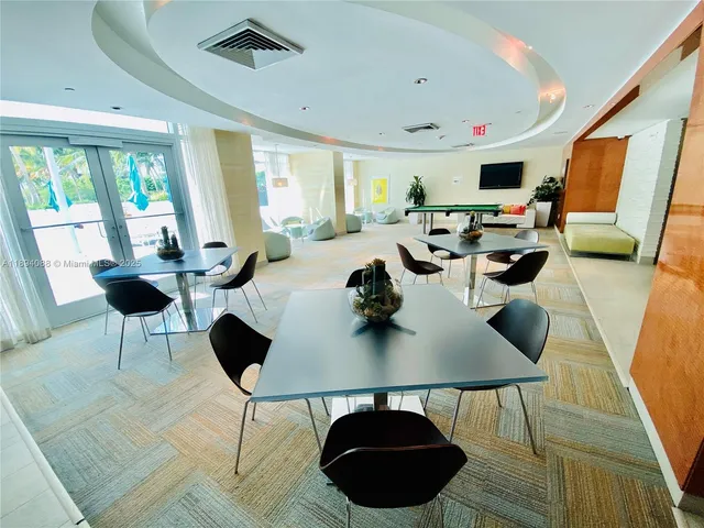a living room with stainless steel appliances furniture and a kitchen view