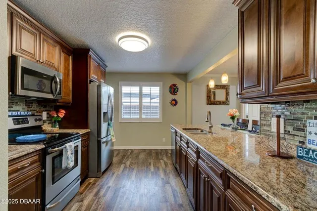 a kitchen with granite countertop stainless steel appliances a stove sink and cabinets
