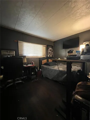 a bedroom with furniture a flat screen tv and a window