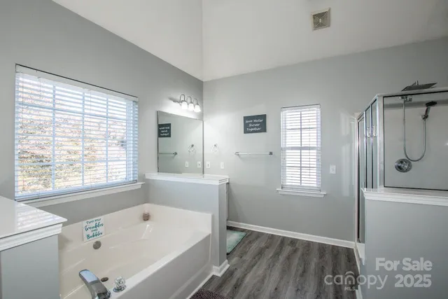 a bathroom with a bathtub a shower a sink and a window