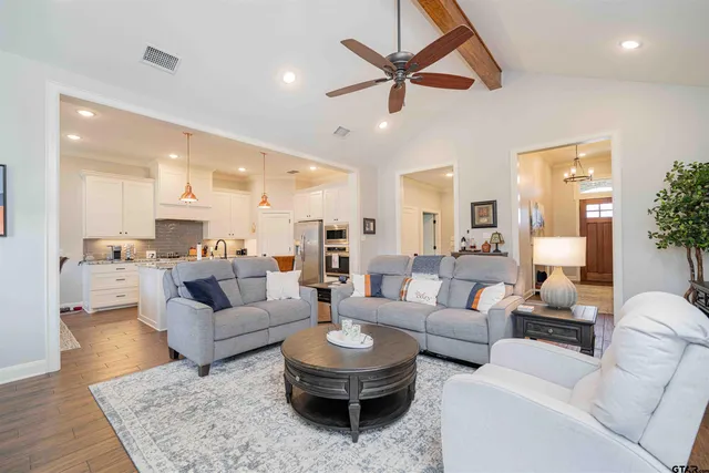 a kitchen with stainless steel appliances granite countertop a stove a sink a refrigerator and white cabinets with wooden floor