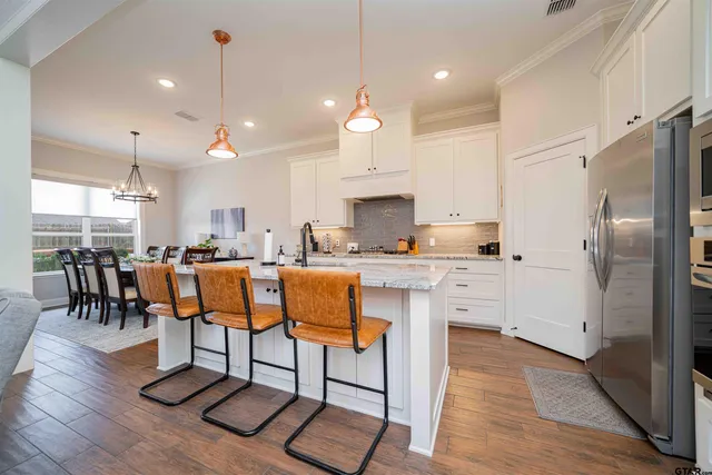 a kitchen with stainless steel appliances kitchen island granite countertop a table chairs in it and wooden floors