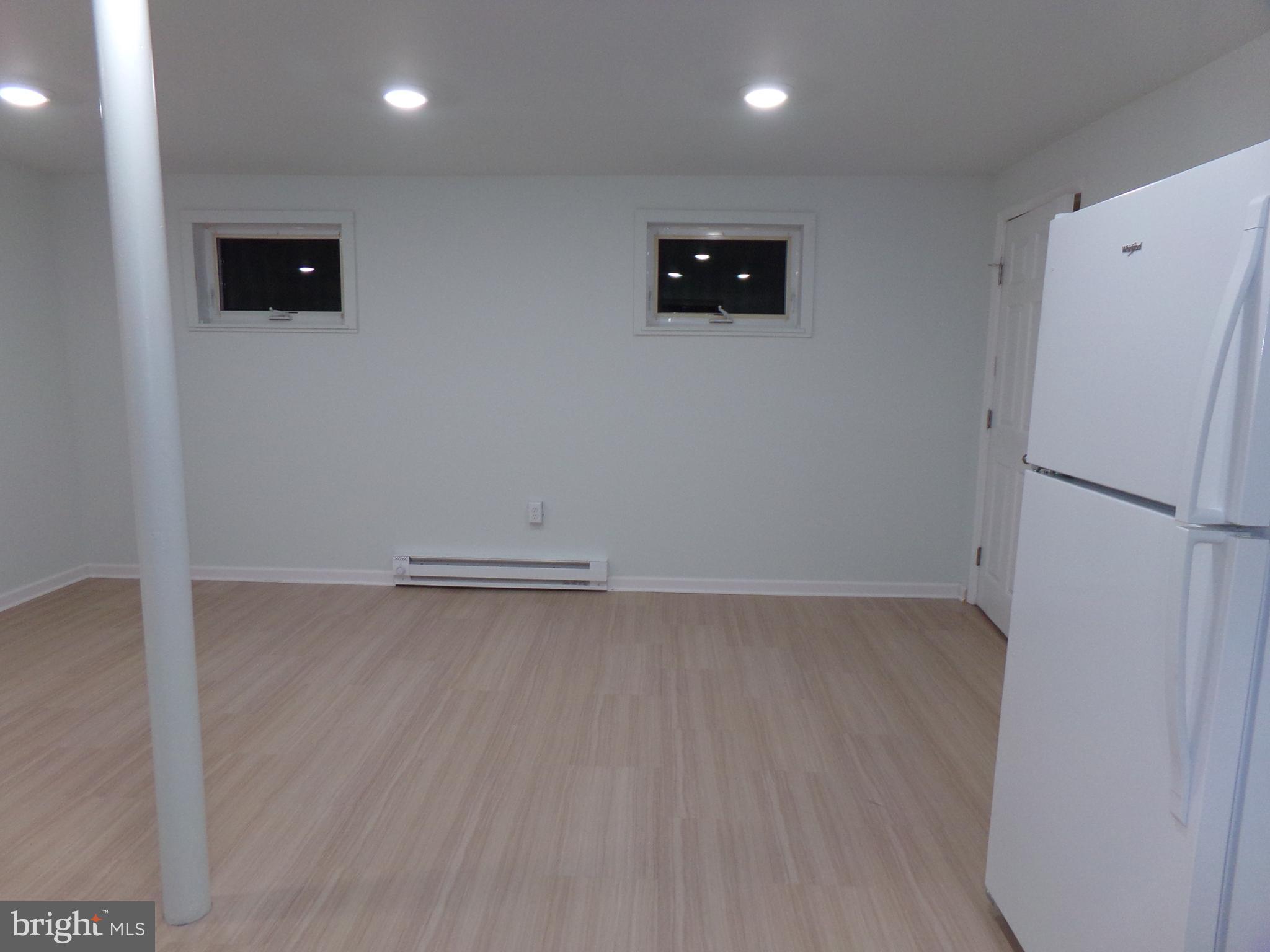 276 East Main Street, Unit 5 Westminster, MD 21157 - Photo 8 of 23 a view of a refrigerator in kitchen and an empty room with wooden floor