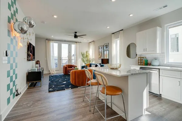 a large white kitchen with stainless steel appliances granite countertop a stove a sink dishwasher and white cabinets with wooden floor