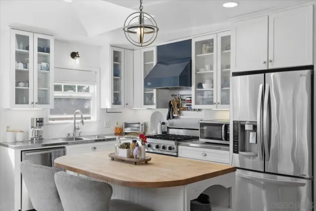 a kitchen with stainless steel appliances a refrigerator a sink a stove and white cabinets