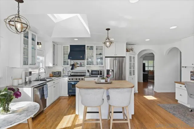 a kitchen with stainless steel appliances granite countertop a stove a sink dishwasher a dining table and chairs with wooden floor