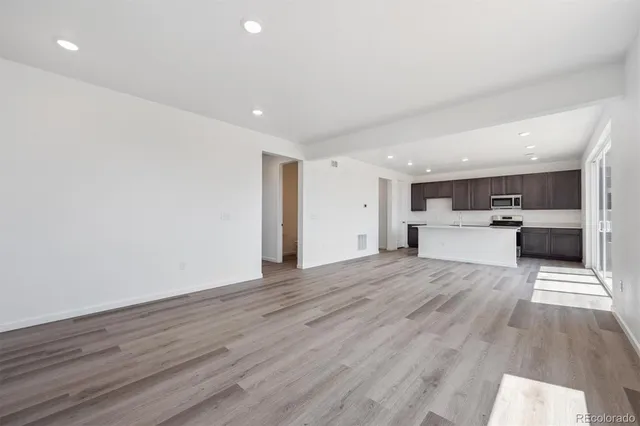 a view of large kitchen with wooden floor and stainless steel appliances