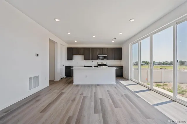 a view of a kitchen with kitchen island a sink wooden floor and a large window