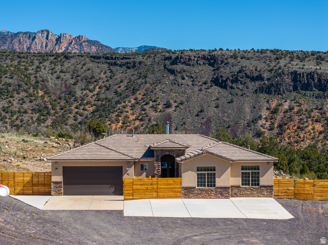 View of front of house featuring a fenced front yard, stone siding, a mountain view, and stucco siding
