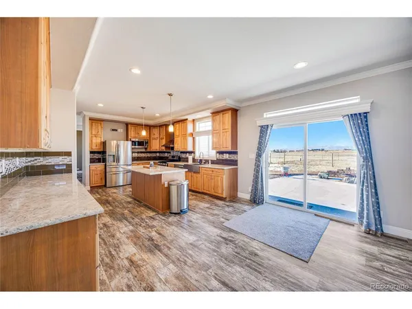 a open kitchen with granite countertop a stove top oven a sink and a refrigerator