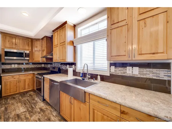 a kitchen with stainless steel appliances granite countertop a sink a stove a counter space and cabinets