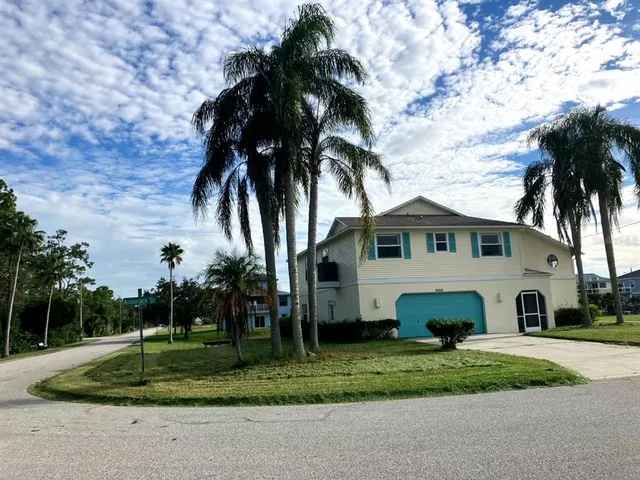 a view of house with a yard and palm trees