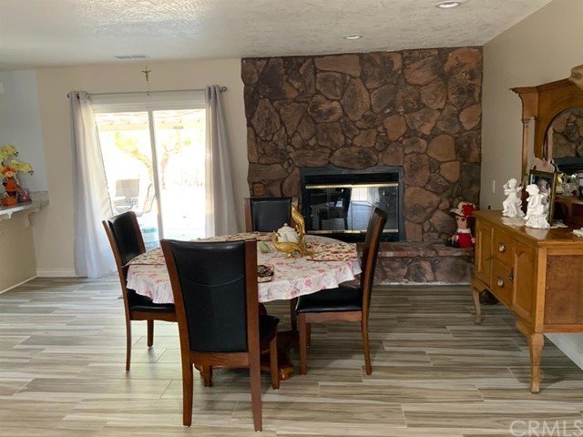 9450 Mango Avenue Hesperia, CA 92345 - Photo 5 of 14 a dining room with furniture a fireplace and wooden floor