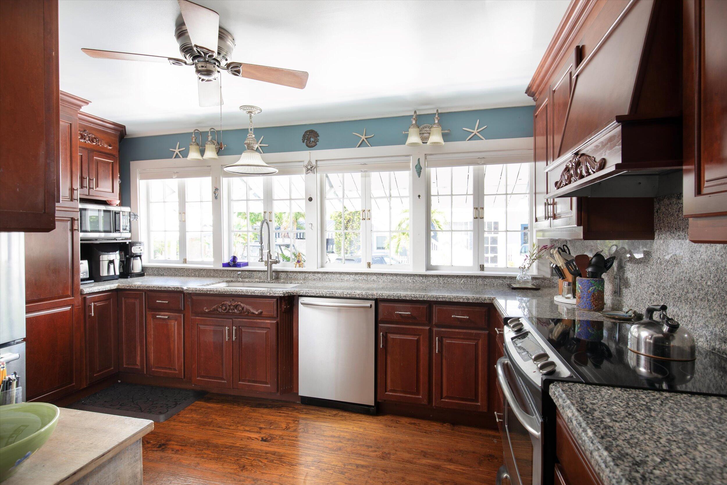 900 White Street, Unit 2 Key West, FL 33040 - Photo 3 of 24 a kitchen with stainless steel appliances granite countertop a sink dishwasher a stove a dining table and chairs with wooden floor