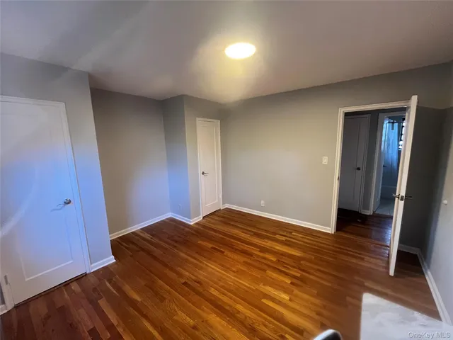 a view of an empty room with wooden floor and closet