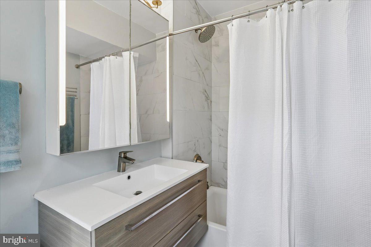 2500 Q Street Northwest, Unit 605 Washington, DC 20007 - Photo 19 of 48 a bathroom with a sink a mirror and a shower curtain