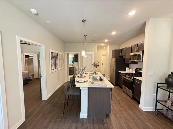 a kitchen with a sink stainless steel appliances and wooden floor