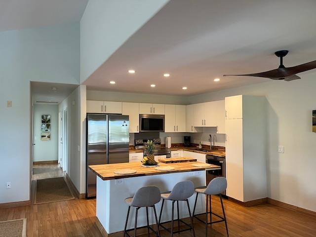 46 Polohina Lane, Unit 5 Lahaina, HI 96761 - Photo 4 of 10 a kitchen with stainless steel appliances a dining table chairs refrigerator and sink