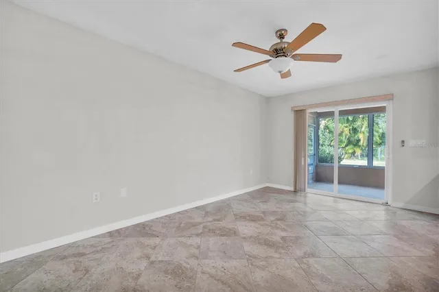 an empty room with ceiling fan and window