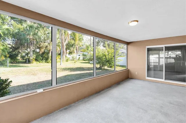 a view of an empty room with wooden floor and a large window with an outdoor view