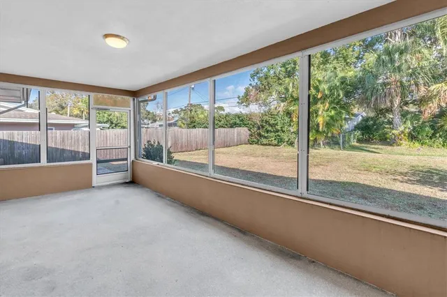 a view of an empty room with wooden floor and a large window with an outdoor view