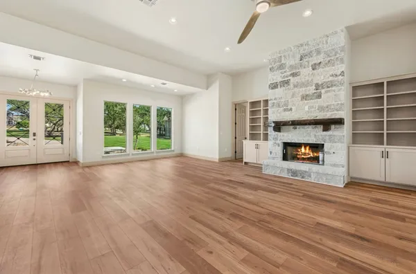 an empty room with wooden floor fireplace and windows