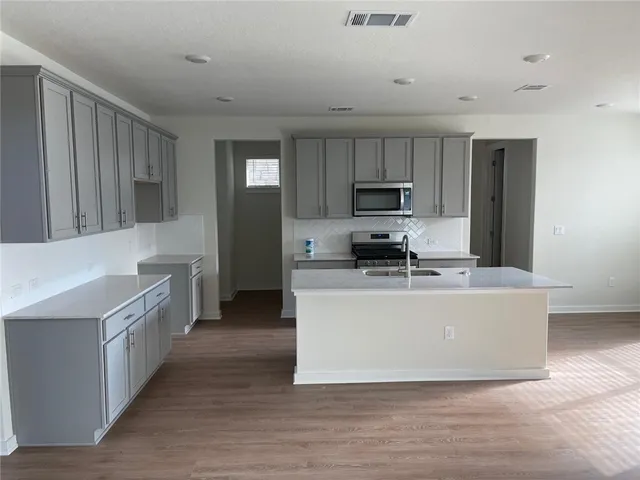 a large kitchen with stainless steel appliances granite countertop a stove a sink dishwasher and a refrigerator with wooden floor