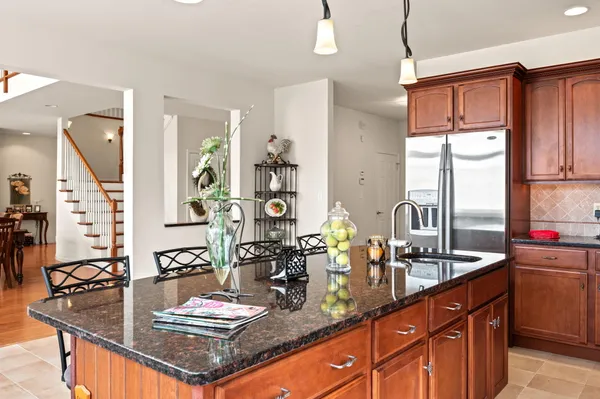 a kitchen with stainless steel appliances granite countertop a stove top oven a refrigerator a sink and chairs