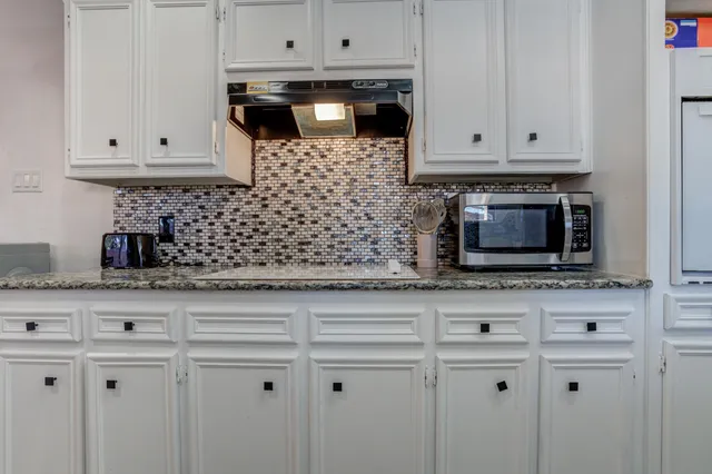 a kitchen with white cabinets and appliances