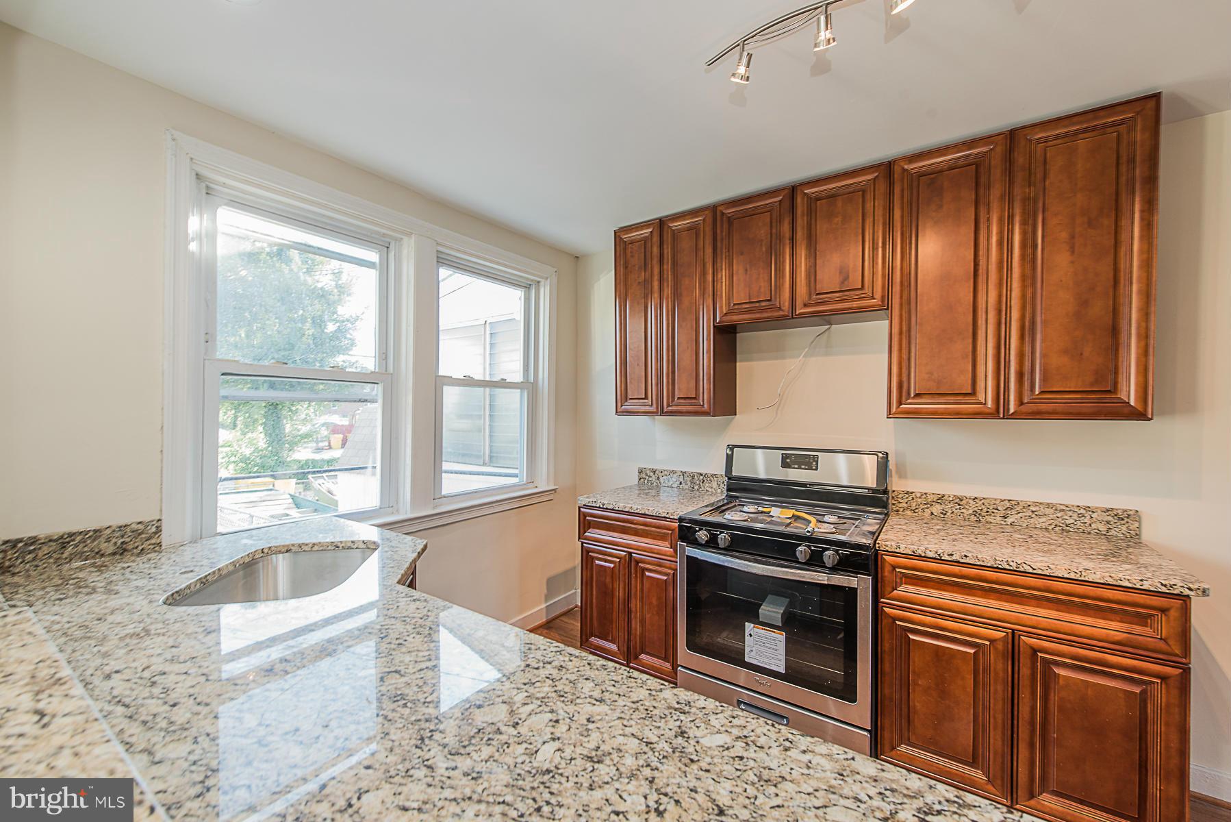 229 West Edgevale Road Baltimore, MD 21225 - Photo 5 of 13 a kitchen with stainless steel appliances granite countertop a stove a sink and a microwave