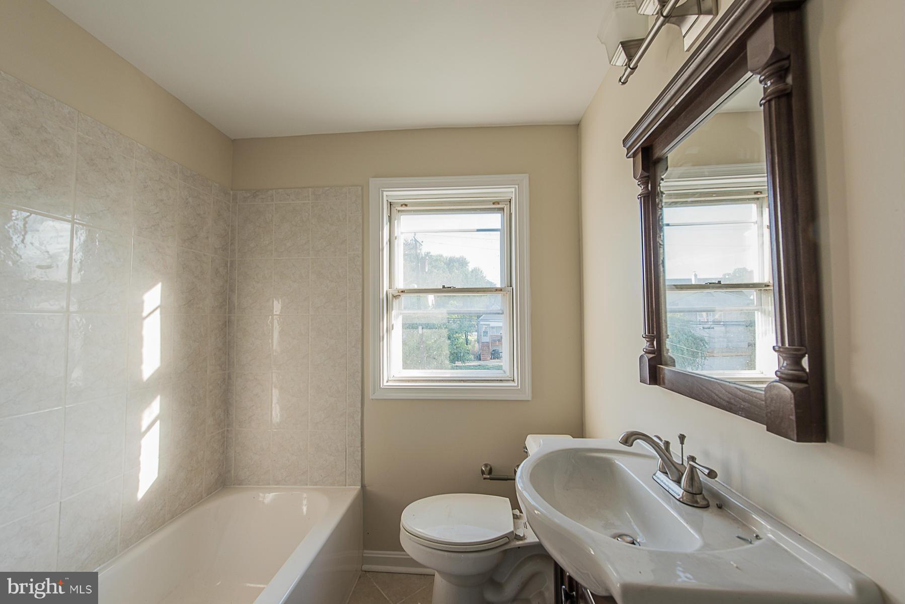 229 West Edgevale Road Baltimore, MD 21225 - Photo 9 of 13 a bathroom with a granite countertop sink toilet a mirror and a tub
