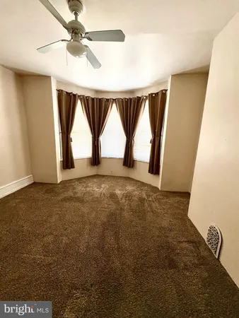 a view of empty room with window and ceiling fan