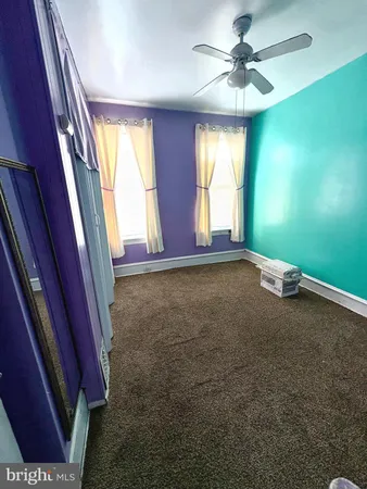 an empty room with windows and ceiling fan