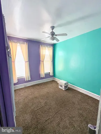 a view of a room with a ceiling fan and carpet