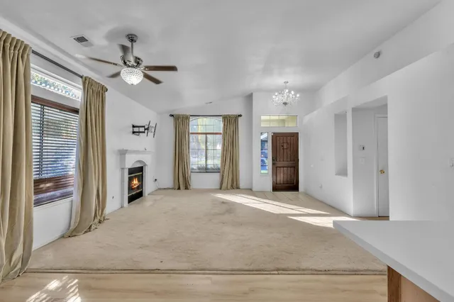 a view of a livingroom with a chandelier fan and windows
