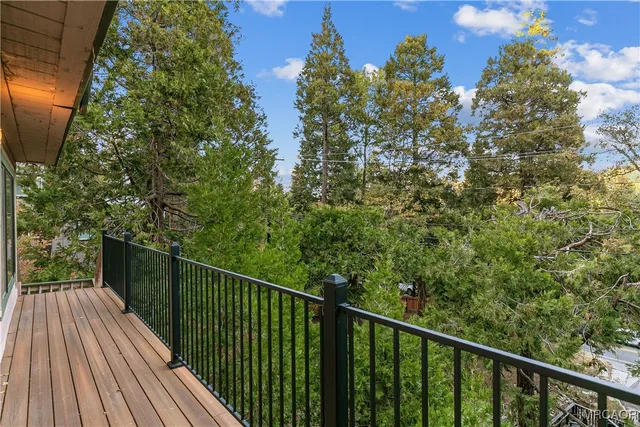 a balcony with wooden floor and trees in the back