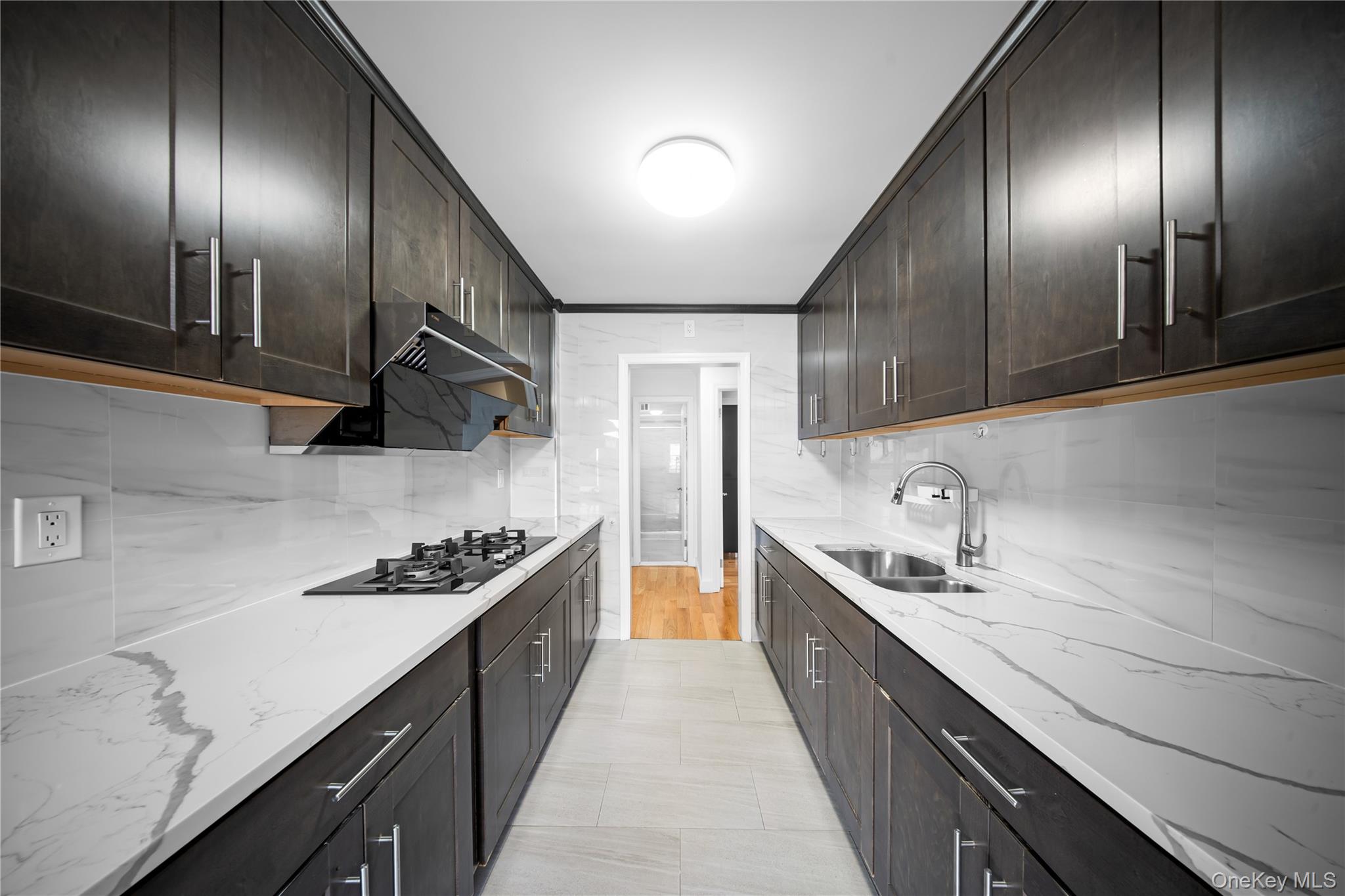 134-54 Maple Avenue, Unit 3W Queens, NY 11355 - Photo 10 of 19 Kitchen with backsplash, light stone counters, and dark brown cabinets