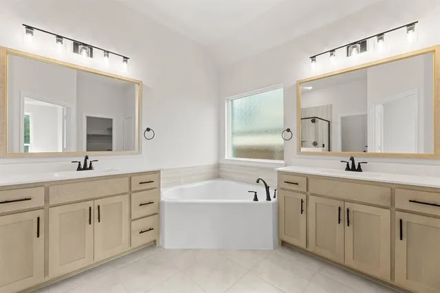 a bathroom with a double vanity sink mirror and bathtub