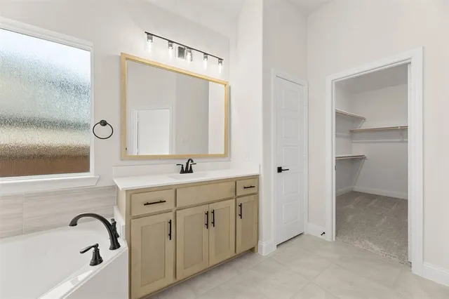 a spacious bathroom with a double vanity sink a mirror and a bathtub