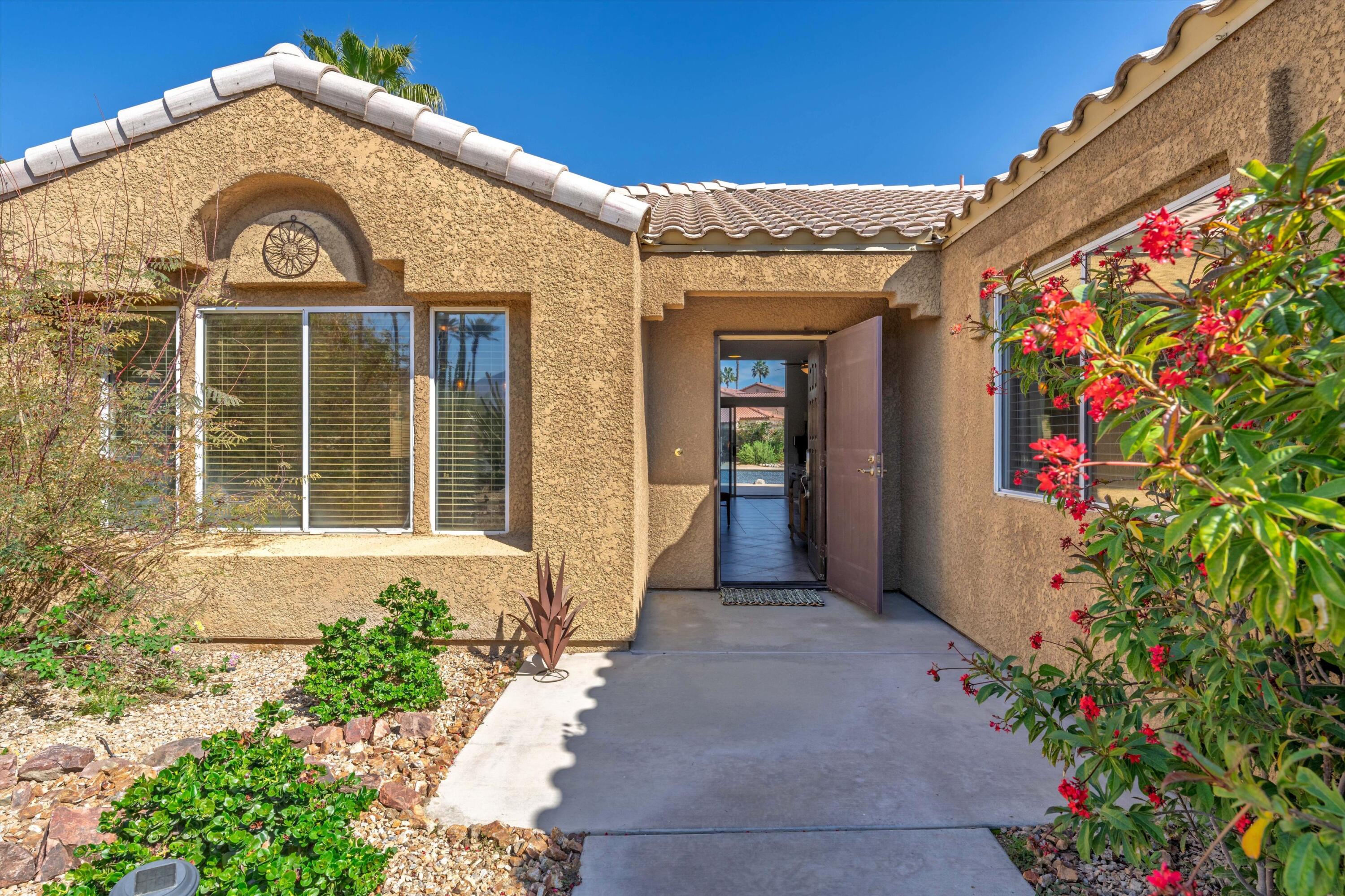 78330 Vía Sevilla La Quinta, CA 92253 - Photo 25 of 49 a view of a brick house with a flower garden