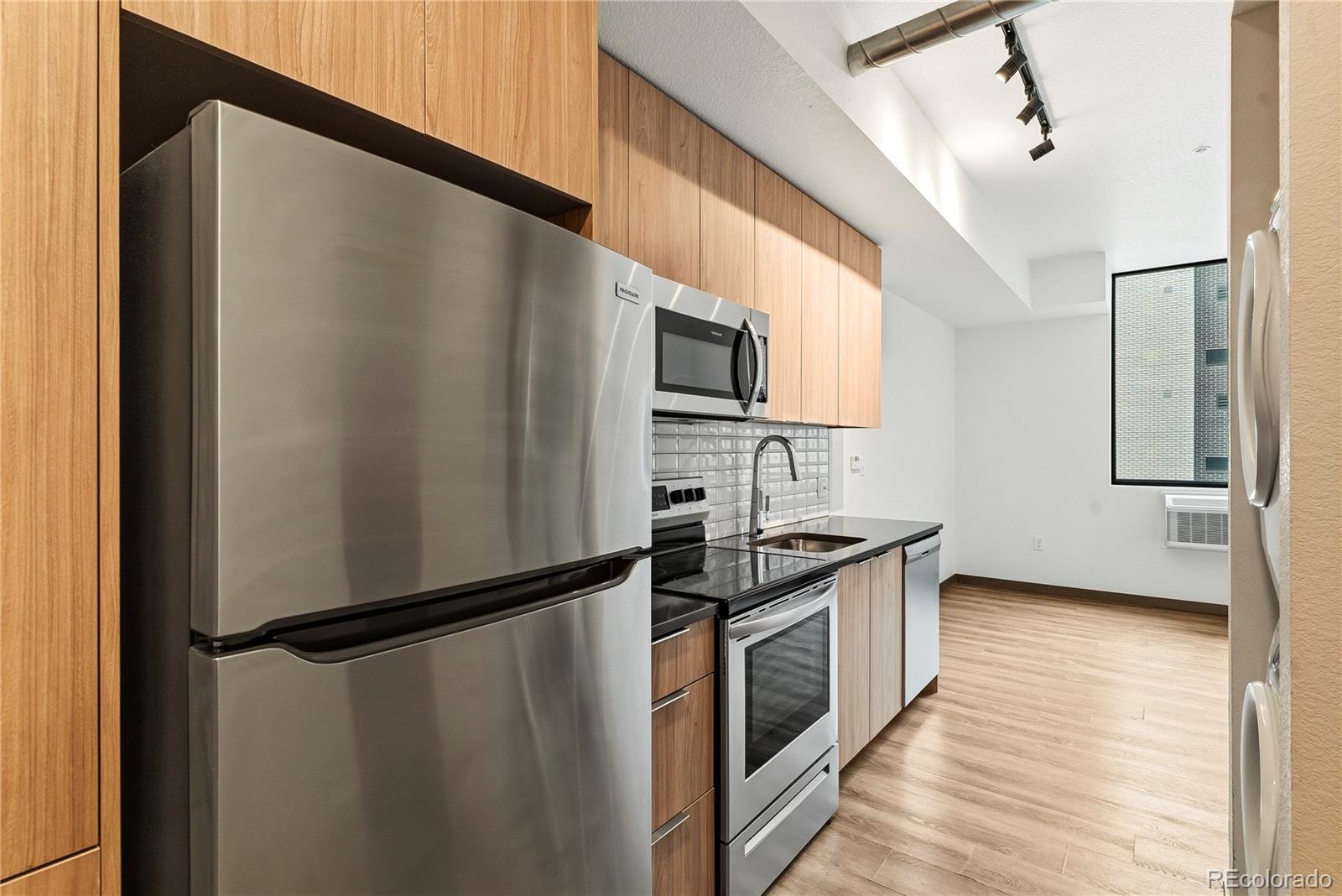 603 Inca Street, Unit 330 Denver, CO 80204 - Photo 16 of 18 a kitchen with stainless steel appliances a refrigerator a sink and white cabinets