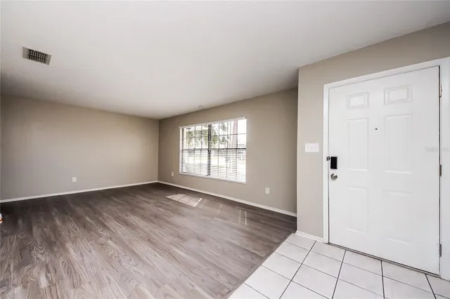a view of an empty room with window and wooden floor