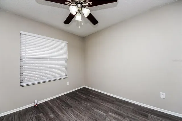 an empty room with a window and a fan