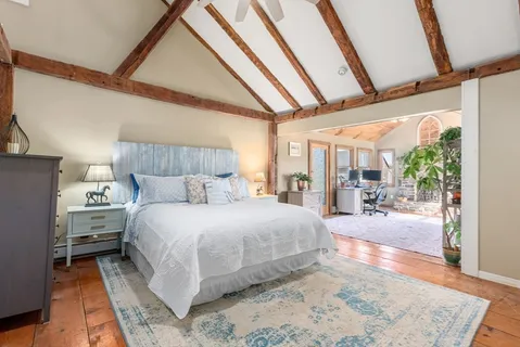 a large bedroom with a bed and wooden floor
