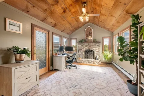 a view of a livingroom with a fireplace a chandelier and windows