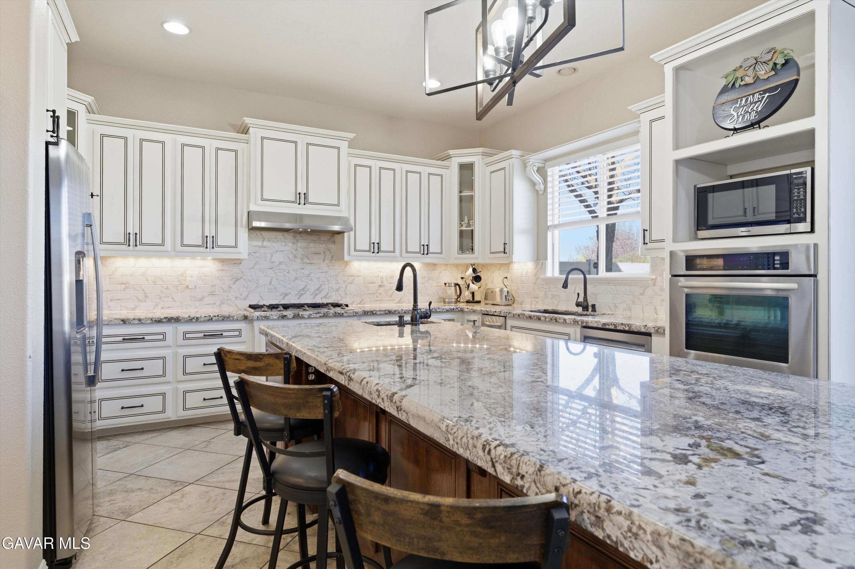 109 Oak Place Tehachapi, CA 93561 - Photo 11 of 25 a kitchen with granite countertop a stove a sink and a microwave