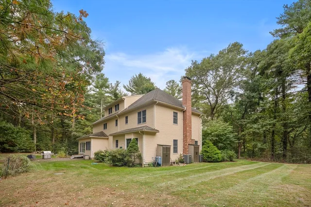 a view of house with a big yard and large trees
